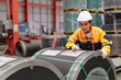 © Nassorn - Female industrial engineer in white helmet and safety jacket work in heavy steel engineering factory. Latin inspector woman inspecting production material in metalwork manufacturing facility, portrait