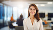 © Jasmina - Portrait of young confidant business woman standing in the office smiling, co-workers and employees in the background