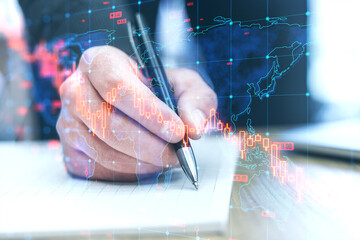 Poster - Close up of businessman hand doing finance paperwork on desk with falling forex chart arrows on blurry background. Financial crisis, trade and recession concept. Double exposure.
