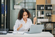 © laddawan - Confident business expert attractive smiling young woman typing laptop and holding digital tablet