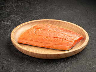 Portion of raw fresh salmon fillet in a wooden plate