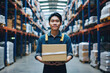 asian warehouse worker holding cardboard box in warehouse