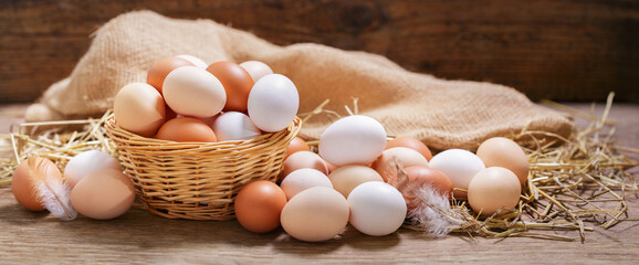 basket of colorful fresh eggs on wooden table