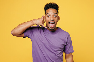 Poster - Young excited man of African American ethnicity he wears purple t-shirt casual clothes doing phone gesture like says call me back isolated on plain yellow background studio portrait Lifestyle concept