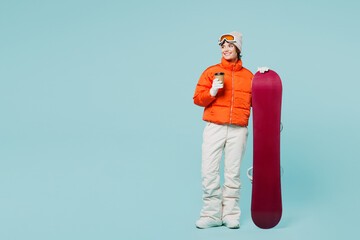 Wall Mural - Full body young woman wear padded windbreaker jacket hat ski goggles mask hold snowboard drink coffee look aside travel rest spend weekend winter season in mountains isolated on plain blue background.