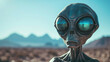 Alien figure in a desert with mountains.