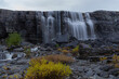 Fotografie von dem eindrucksvollen Orvvosfossen Wasserfall in Skandinavien, welcher sich durch das vom Regen gefärbten dunklen Gestein seinen Weg bahnt.