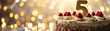 Celebration cake with a glittering golden '5', perfect for a 5th birthday or anniversary. Shiny number five, bokeh lights. Special event. Panoramic banner with copy space for text.