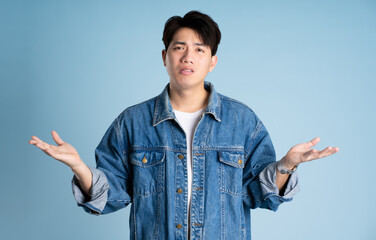 Portrait of an Asian guy wearing a jacket posing on a blue background