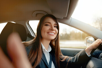 Smiling young woman taking selfie picture with camera in car.  Beautiful young woman in car, taking selfie.