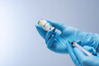 Doctor in blue latex gloves fill in syringe with vaccine from glass vial. Vaccination, immunization, treatment to Covid 19 Corona Virus infection. Healthcare And Medical concept.