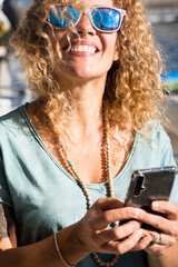 Summer holiday vacation happy cheerful beautiful woman portrait - pretty caucasian female people smile and use cellular phone outdoor with boats in background enjoying holidays seasons