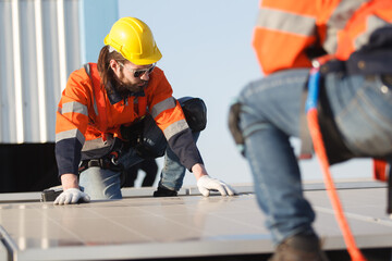 Professional electric engineers survey and inspect solar panels installation on the factory metal sheet roof top, electric engineer team inspecting and check solar cell system.