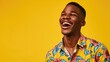 © mashimara - A young man in an orange shirt laughs joyfully against a yellow background, capturing a moment of genuine happiness and carefree spirit.