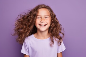 Portrait of a smiling little girl with long curly hair on purple background