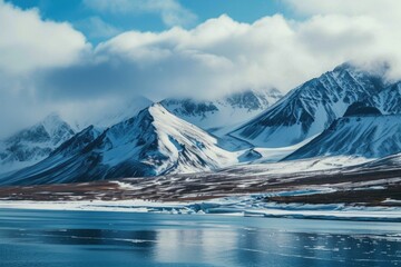 Poster - Snow covered mountains create a stunning backdrop to a tranquil body of water. Perfect for nature enthusiasts and travel publications