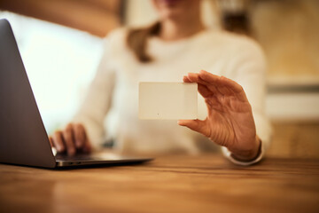 A close-up of a female holding a credit card while working online.