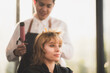 © chokniti - Asian Hairdresser giving treatment and barber occupation service, Professional hairstylist combing and using scissors cut woman's hair to young beautiful customer girl in beauty salon