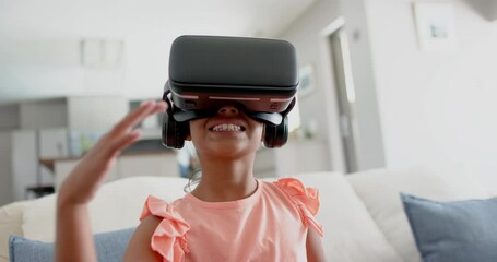 Wall Mural - happy biracial girl wearing vr headset using virtual interface at home, slow motion