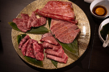 Variety of raw beef meat steaks for grilling with seasoning and utensils on dark rustic board, red tone of fresh food in raw cut