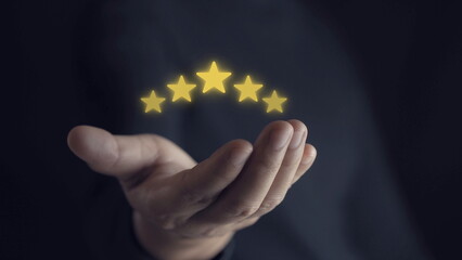 Wall Mural - hand of customer or client holding the stars to complete five stars. with copy space. giving a five star rating. Service rating, satisfaction concept.
