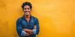 © ckybe - A content young Latino male posing with folded arms and a joyful expression against a yellow backdrop.