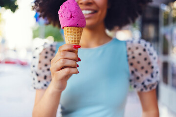 Wall Mural - Smiling cute mixed race girl walking down the street and holding pink ice cream