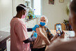 © Marko Geber - Senior man receiving a vaccine at home with healthcare worker