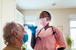 © Marko Geber - Healthcare worker testing senior patient for coronavirus at home