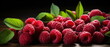 A close up of a pile of fresh raspberries with green leaves on a wooden table against a dark background