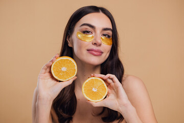 woman standing naked isolated looking camera take care of her skin with under eye gold patches