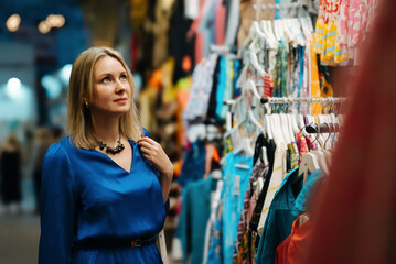 Wall Mural - Woman choosing a clothes at the evening bazaar.