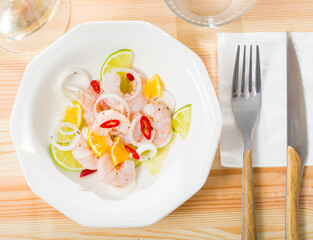 Wall Mural - Delicious shrimp ceviche with lime, tangerine, onion and hot pepper served on white plate