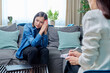 Sad young woman at therapy session with psychologist