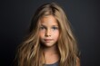 Portrait of a cute little girl with long blond hair. Studio shot.