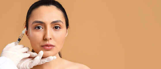 Poster - Young woman receiving filler injection in face against beige background with space for text