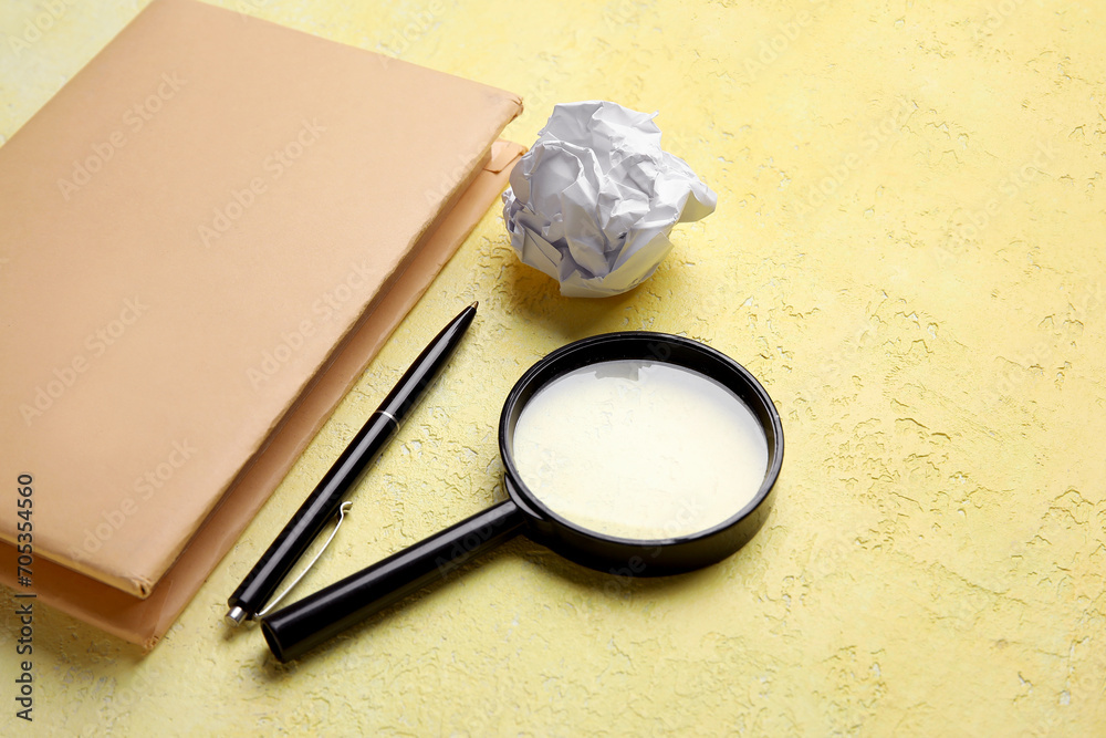Book, pen, magnifier and crumpled paper on color background. World Poetry Day celebration