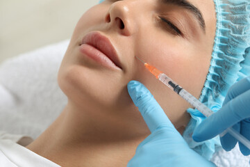 Wall Mural - Doctor giving facial injection to young woman in clinic, closeup. Cosmetic surgery