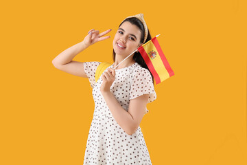 Canvas Print - Pretty young woman with flag of Spain and backpack on yellow background