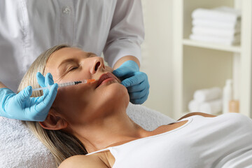 Wall Mural - Doctor giving lips injection to senior woman in clinic. Cosmetic surgery