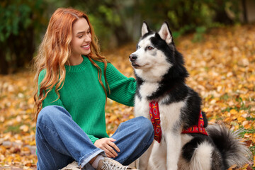 Canvas Print - Happy woman with cute Siberian Husky sitting in autumn park