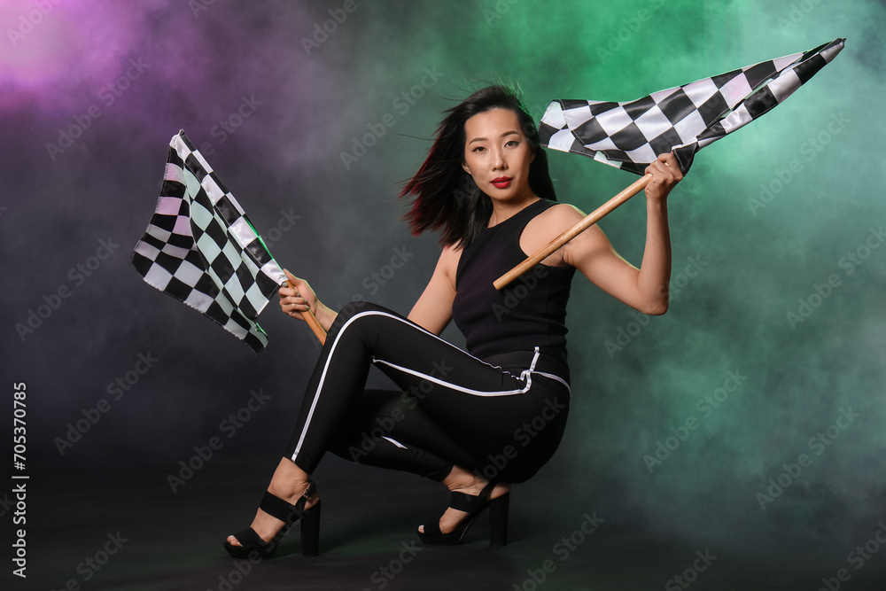 Beautiful Asian woman with racing flags on dark background