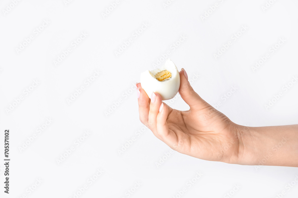 Female hand holding boiled chicken egg on white background
