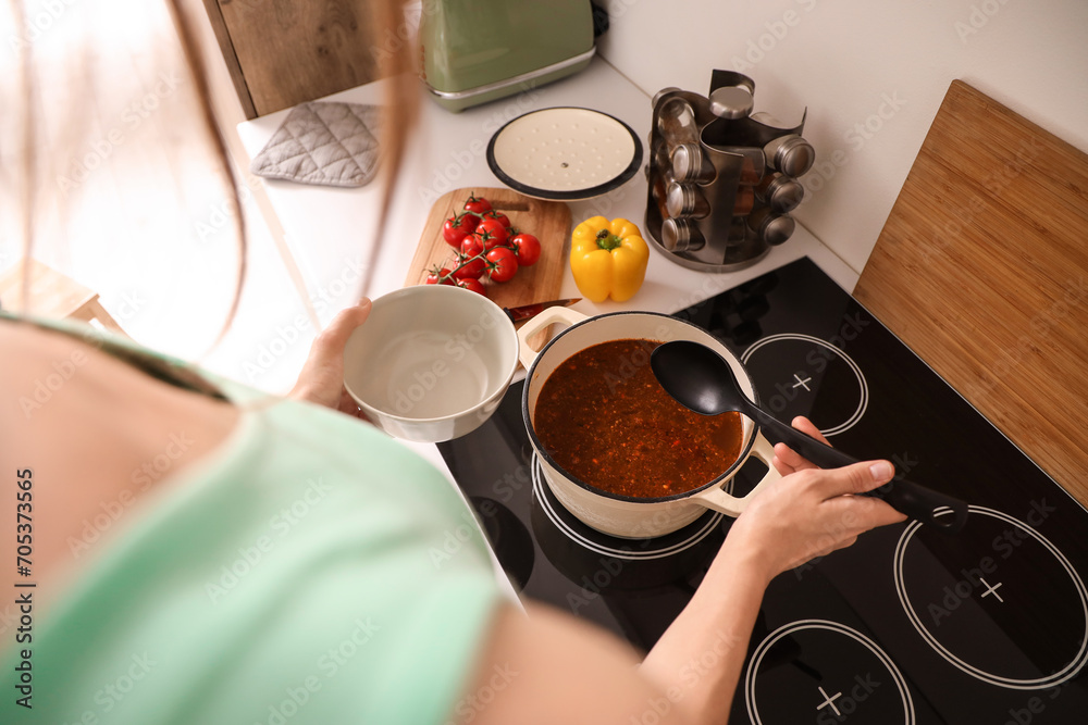 Young woman making soup in kitchen, closeup