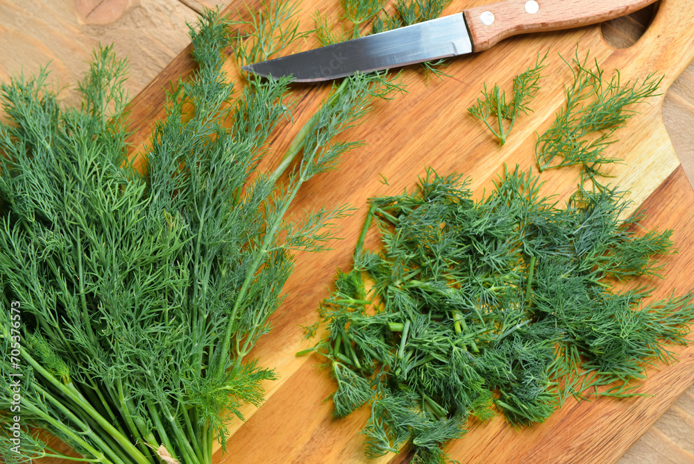 Board with fresh dill on wooden background