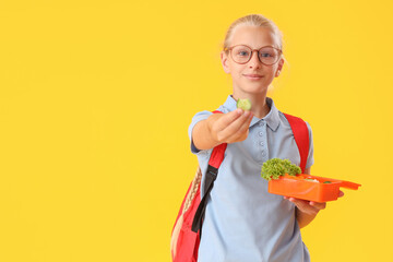 Canvas Print - Girl in eyeglasses with backpack and lunchbox on yellow background