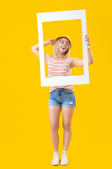 Poster - Young beautiful happy woman with frame on yellow background