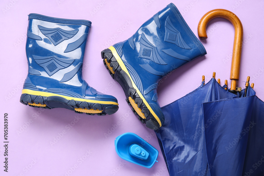 Blue gumboots and umbrella on lilac background
