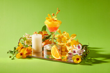 A mirror tray full with fresh flowers, delicious cup of smoothie and candle decorated on a green background. Front view, creative scene for advertising and space for design