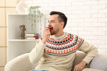 Sticker - Handsome man eating apple on sofa at home